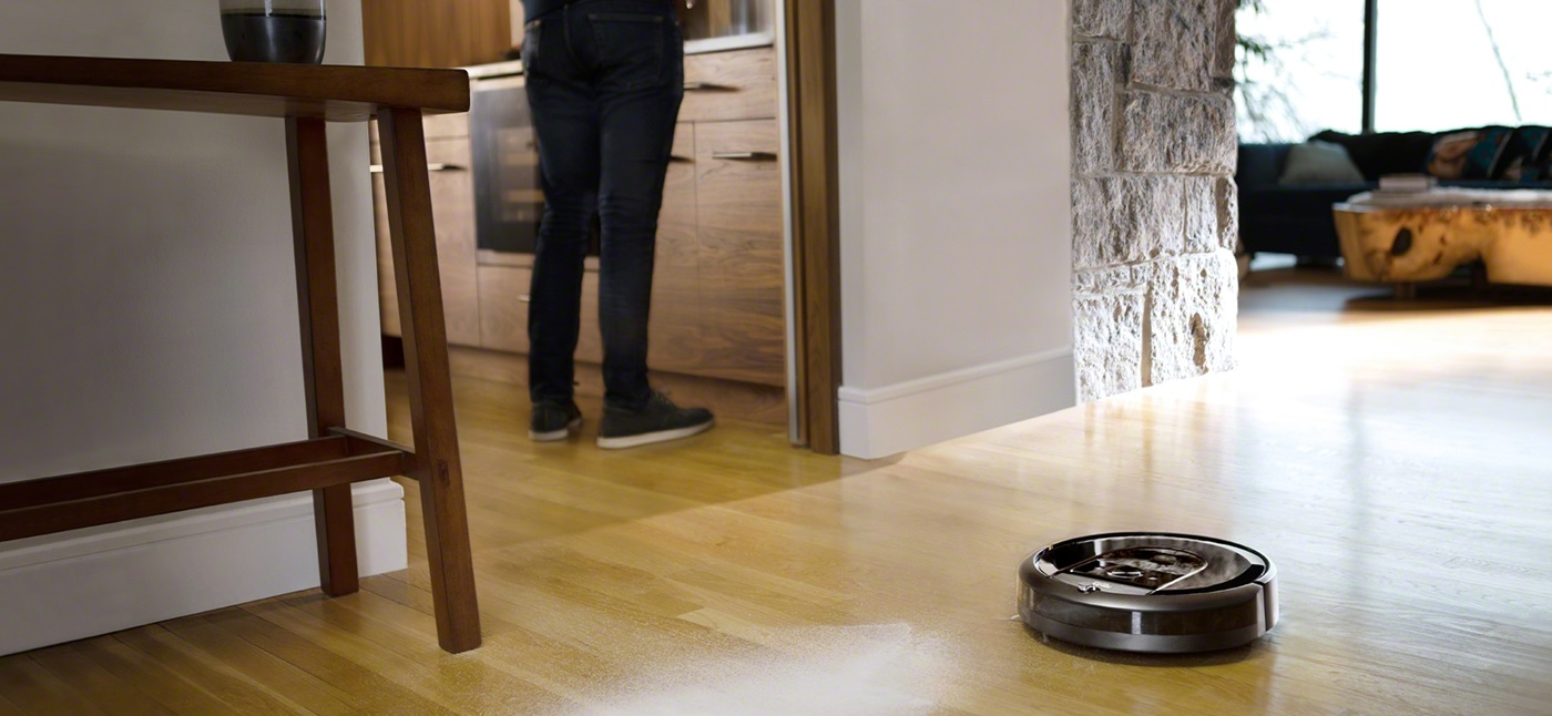 iRobot Roomba i7 odkurza drewnianą podłogę, w tle nogi mężczyzny