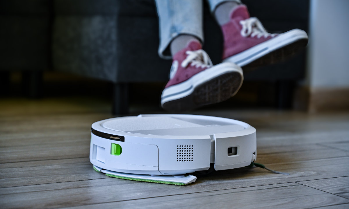 Roomba Combo mopuje panele przejeżdżając obok kanapy na której siedzi kobietas
