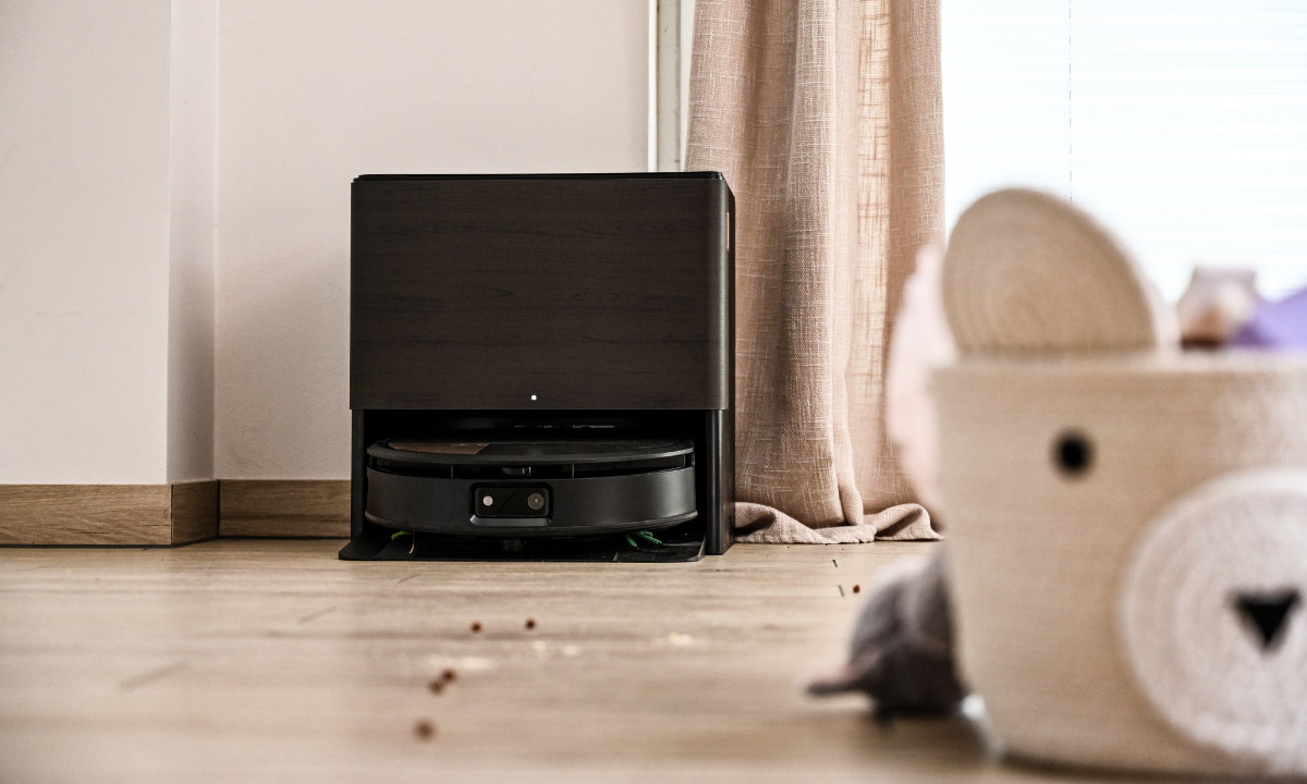 Roomba Combo stoi w stacji AutoWash w salonie, dookoła zabawki dziecięce