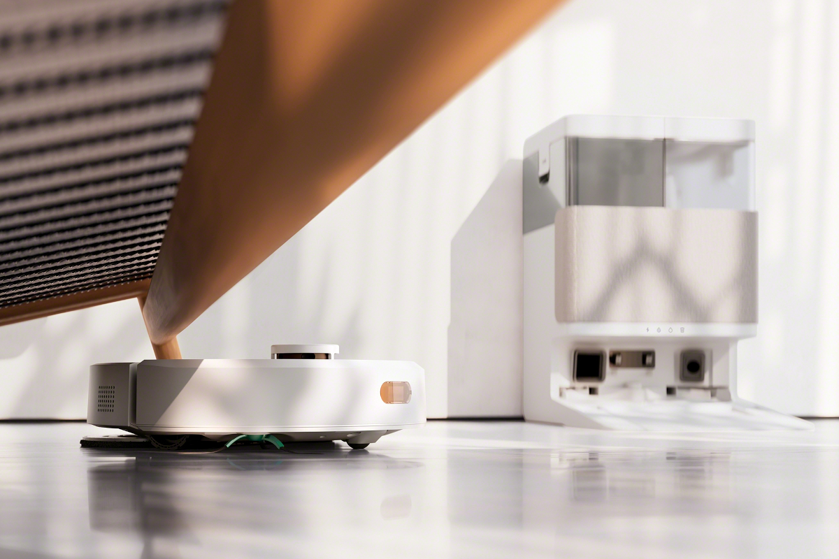 Roomba 405 wyjeżdzą spod kanapy, w tle stacja AutoWash