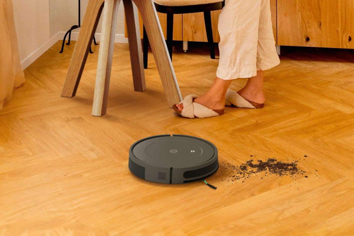 Roomba odkurza piach przy stole