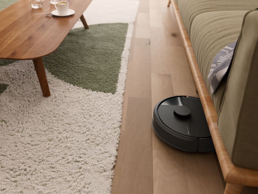 Robot sprzątający Roomba wyjeżdża spod sofy w salonie jadąc w kierunku stolika kawowego stojącego na dywanie