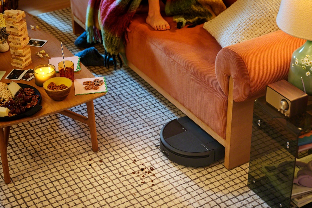 Robot sprzątający Roomba 205 Combo wyjeżdża spod pomarańczowej kanapy na dywan