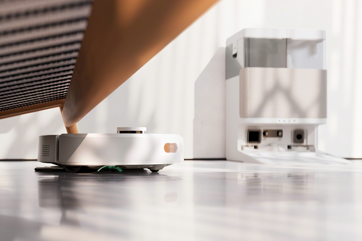 iRobot Roomba 405 wyjeżdża spod kanapy, w tle stacją AutoWash