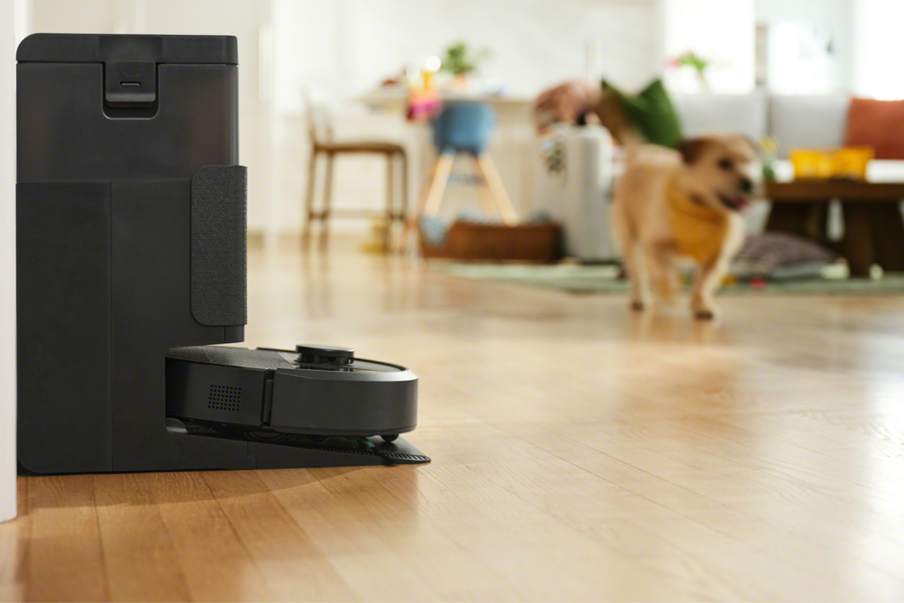 Roomba 405 Combo w stacji dokującej, w tle biegnie pies