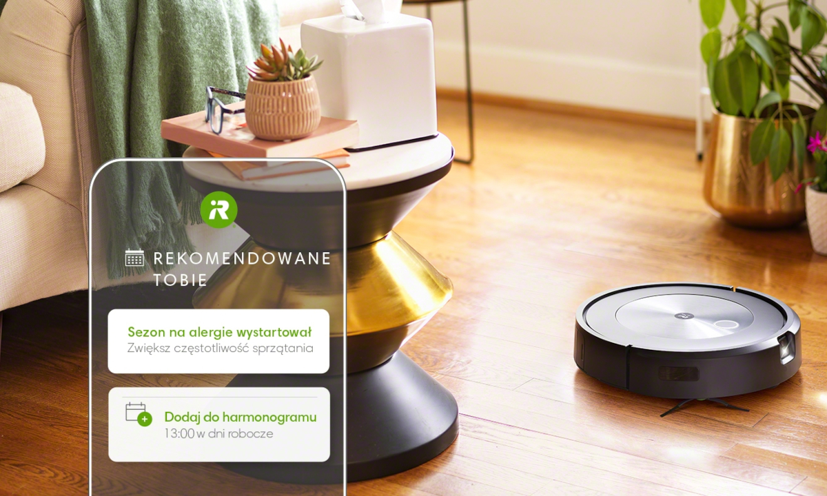 Na podłodze automatyczny odkurzacz Roomba otoczony kwiatami – pomaga alergikom w utrzymaniu czystego domu.