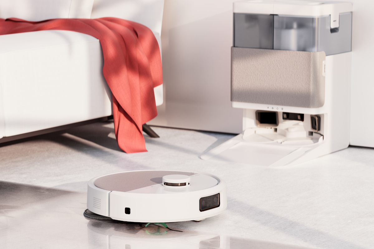 iRobot Roomba 405 wyjeżdża spod kanapy, w tle stacja AutoWash