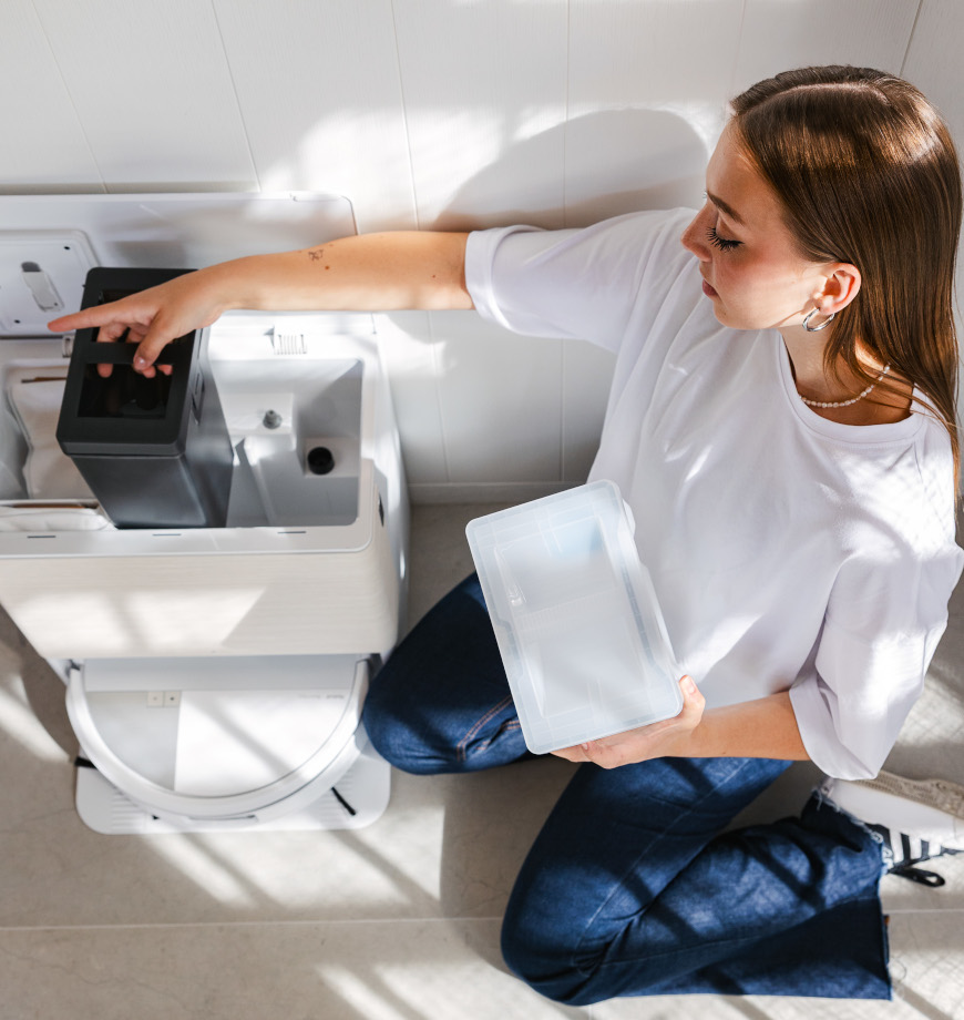 Młoda kobieta ubrana na sportowo wymienia wodę w zbiornikach w stacji dokującej AutoWash