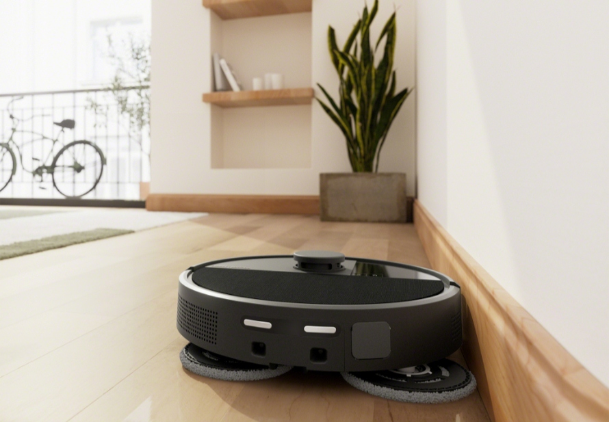 Roomba Plus 505 Combo sprząta w salonie wymiatając brud wzdłuż krawędzi, na drugim planie widać roślinę doniczkową i regał