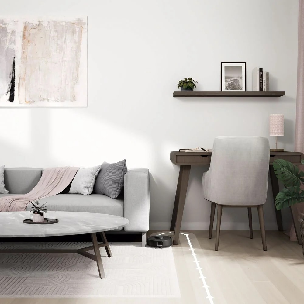Roomba Mini sprząta w równych liniach w salonie obok sofy i biurka z krzesłem