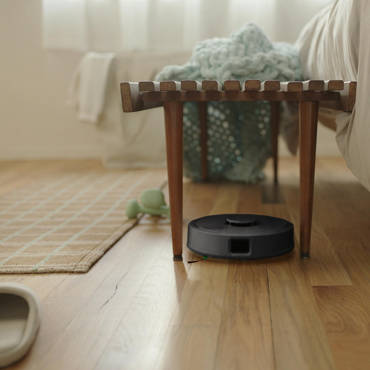 Robot Roomba Mini przejeżdża między nogami stołka w salonie