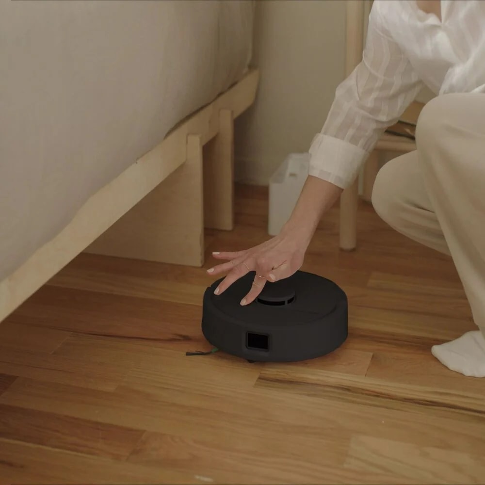 Kobieta naciska na przycisk sprzątania na robocie Roomba Mini Combo, uruchamiając sprzątanie w sypialni