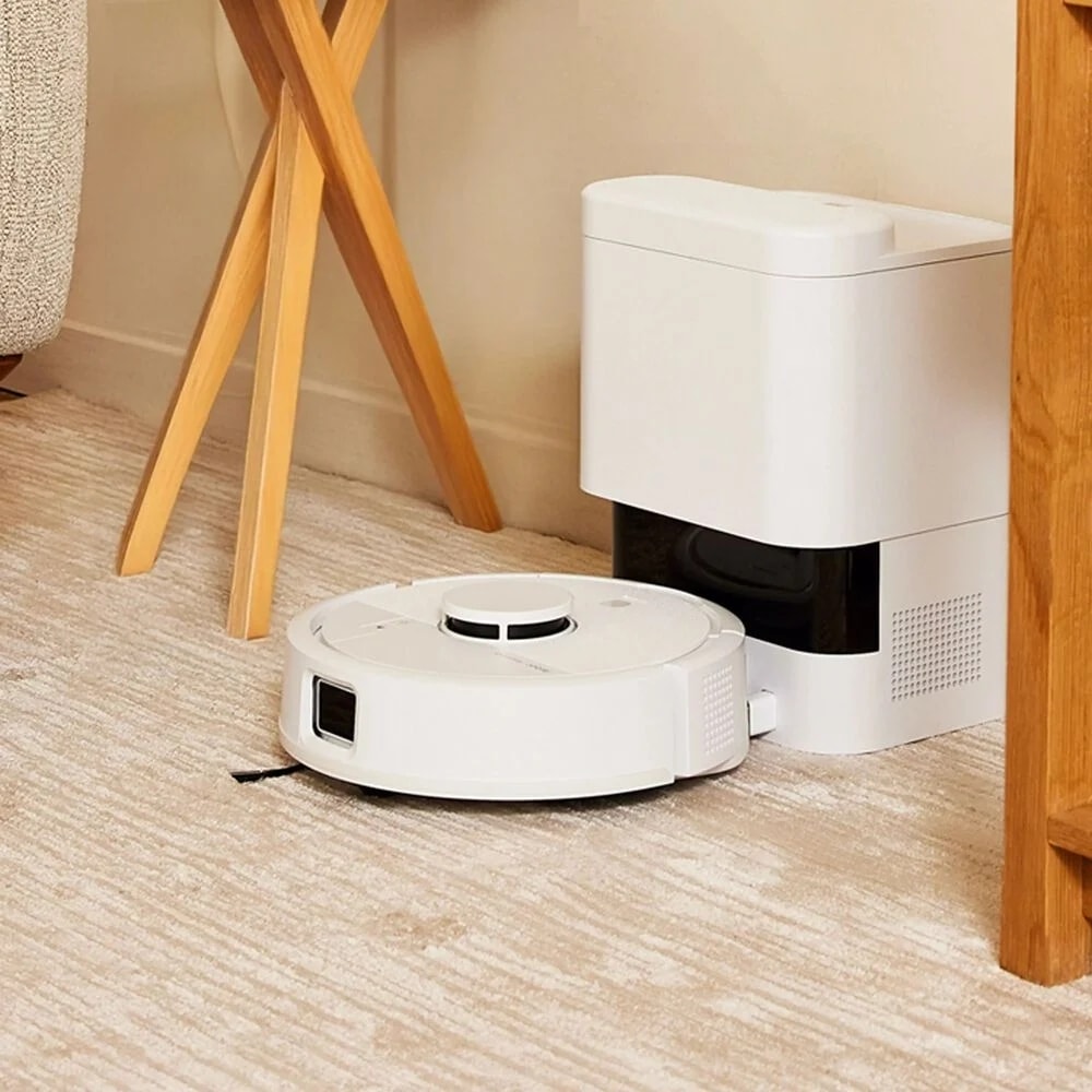 Roomba Mini Combo ładuje akumulator w stacji dokującej AutoEmpty stojąc w ciasnym kącie mieszkania