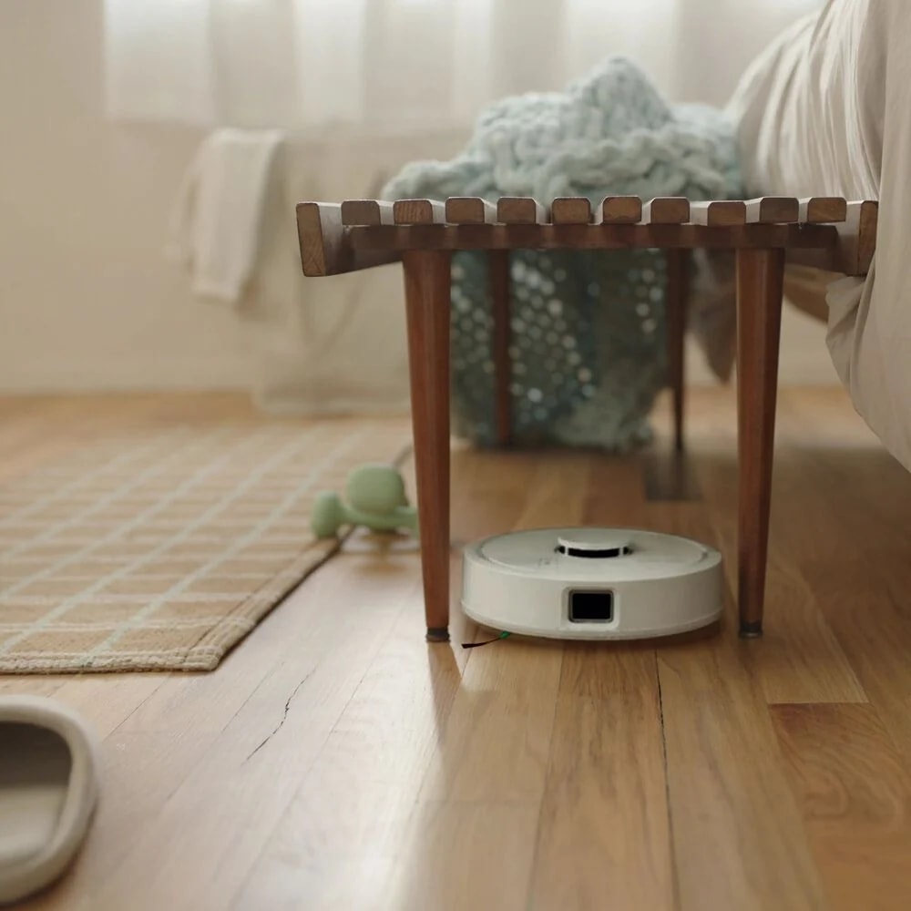 Robot Roomba Mini przejeżdża między nogami stołka w salonie