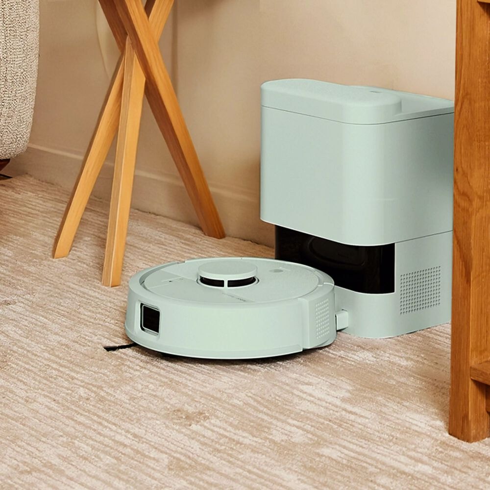 Roomba Mini Combo ładuje akumulator w stacji dokującej AutoEmpty stojąc w ciasnym kącie mieszkania