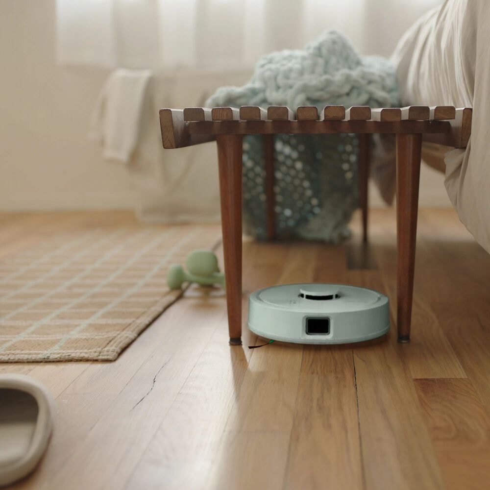 Robot Roomba Mini przejeżdża między nogami stołka w salonie