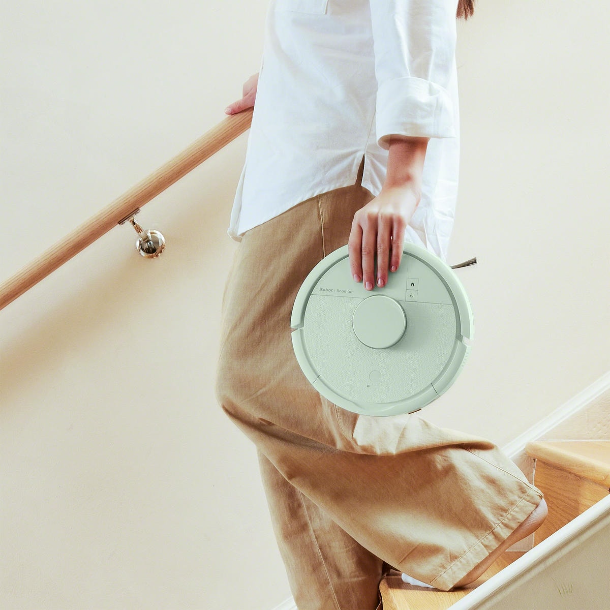 Kobieta schodzi po schodach i niesie w ręku robota Roomba Mini Combo