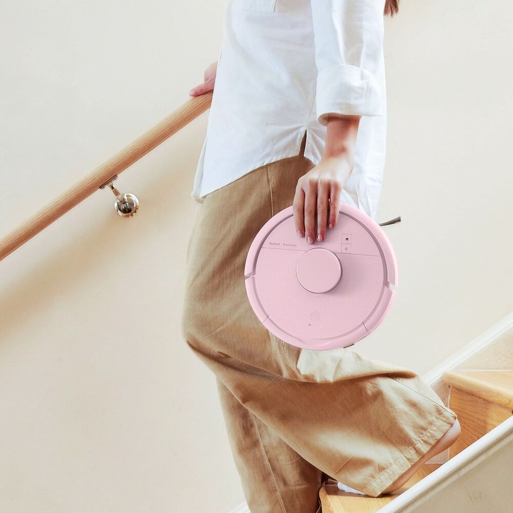 Kobieta schodzi po schodach i niesie w ręku robota Roomba Mini Combo