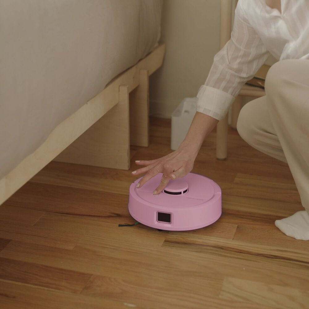 Kobieta naciska na przycisk sprzątania na robocie Roomba Mini Combo, uruchamiając sprzątanie w sypialni