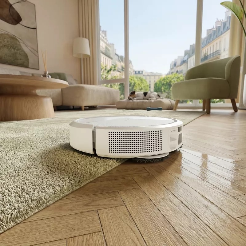 Robot Roomba 415 odkurza i mopuje twardą podłogę w salonie kierując się w stronę dużego okna balkonowego