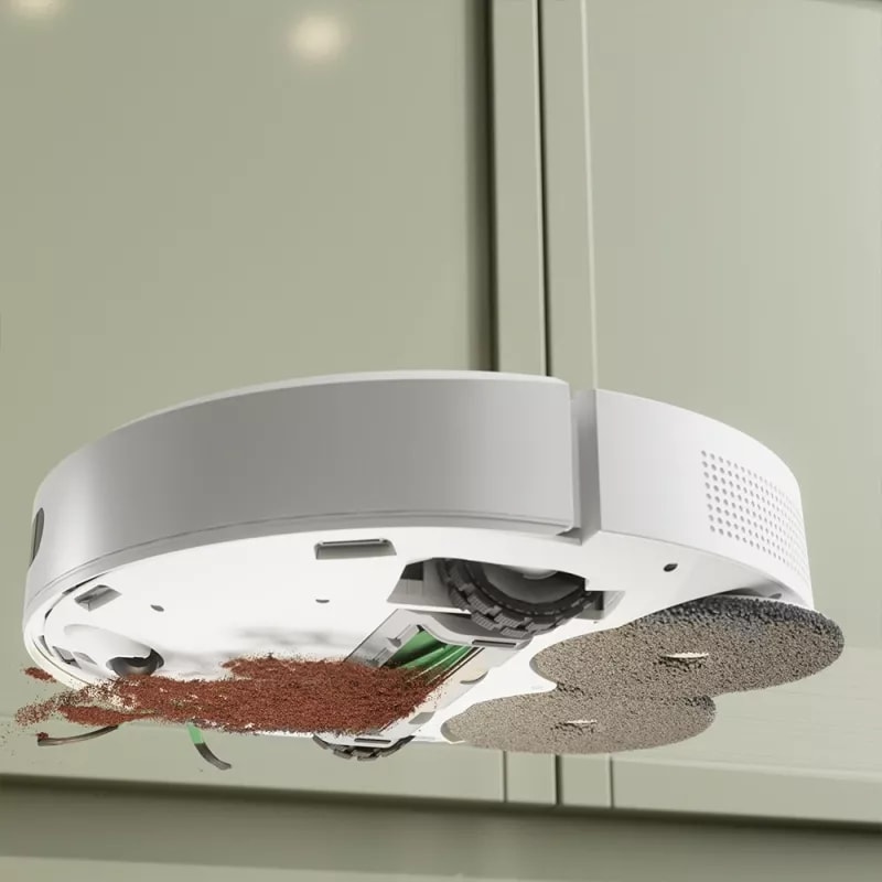Widok spod robota pokazujący jednoczesne odkurzanie rozsypanej kawy